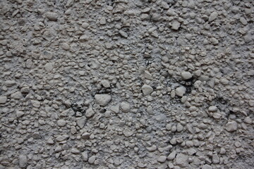 Rough gray dry concrete surface interspersed with crushed stone close up industrial background texture