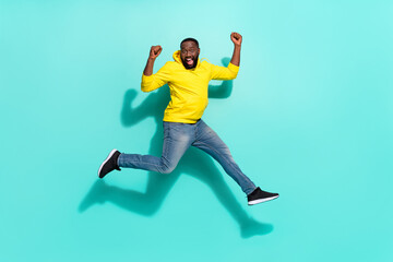 Full size photo of excited delighted guy youngster jump raise fist up isolated over cyan color background