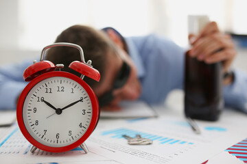 Red vintage clock show time, drunk man fell asleep on workplace in office
