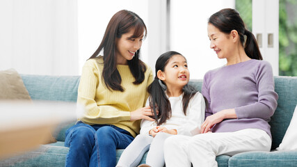 Obraz premium ソファーに並んで座る3世代家族