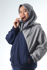 portrait of Asian woman wearing casual clothes. hooded woman wearing a gray jacket on a white background. women with happy expressions eating biscuits or snacks