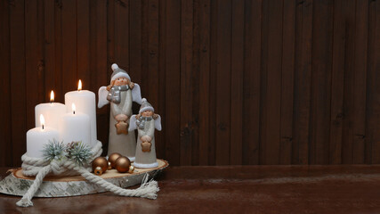Weihnachtshintergrund: Weiße Kerzen mit Engeln auf einer Baumscheibe.