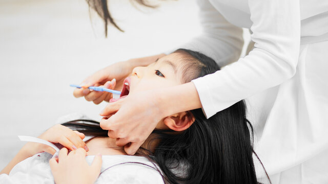 子供の仕上げ磨きをする母親