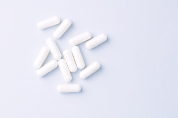 Arginine capsules. Bright paper background. Soft focus. Top view. Close up. Copy space.