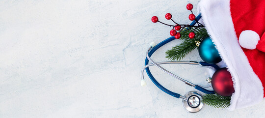 banner with Stethoscope with branches of Christmas tree and Christmas balls in Santa Claus hat. All on white concrete table. Concept Merry Christmas and Happy New year or Healthy New Year. Copy space.
