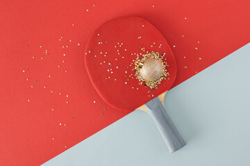 Creative concept with ping pong racket and christmas tree ball on pastel red and blue background. Minimal Christmas concept background.