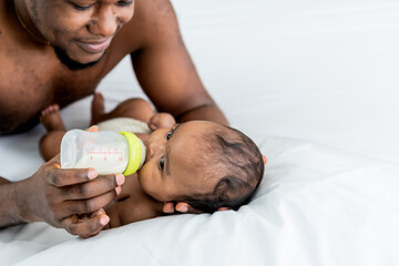 Blurred soft of African black skin  father feeding milk from bottle milk to his  baby newborn...