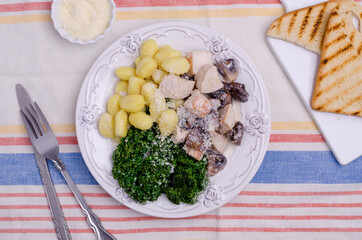 Gnocchi with vegetables and meat in a white sauce.
