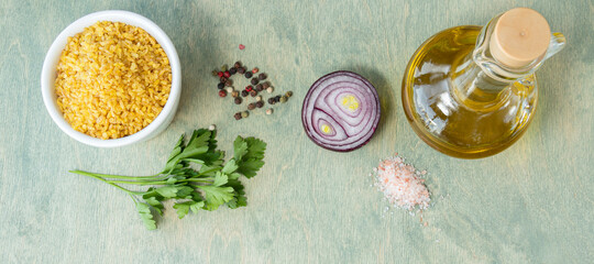 banner with bulgur in white plate with onion, parsley pepper, and pink salt. recipe, food composition, nutrition concept. bulgur with spices and olive oil on wooden background. Flatlay
