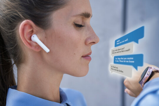 Businesswoman with in-ear headphones using smart wristwatch