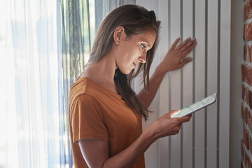 Woman checking temperature of radiator through digital tablet at home