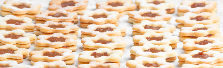 High angle compressed studio shot of traditional Christmas sweets, line dough with apricot ham, powdered with sugar, on white baking paper. Christmas theme background or texture.