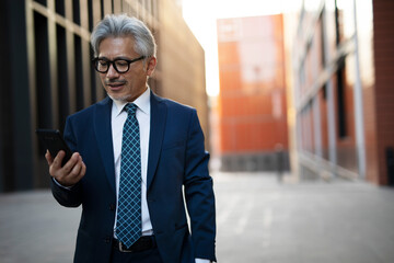 Senior businessman outdoors. Middle-aged businessman using the phone.