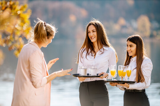 Female event planner instructing waitress holding drink trays
