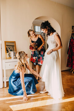 Happy female friends preparing bride in domestic room
