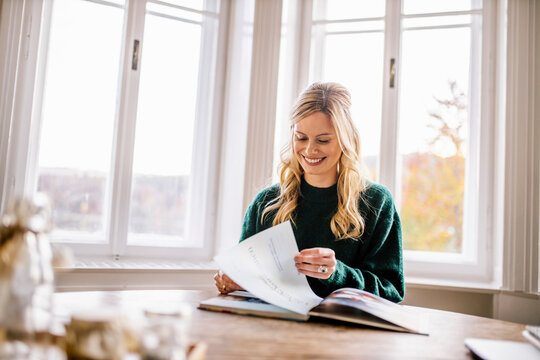Smiling female freelancer looking at photo album in office