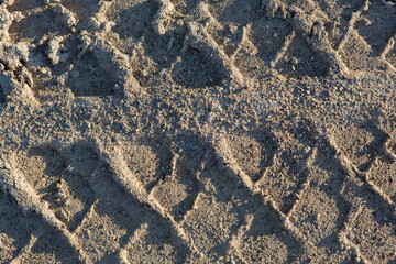 detailed filled frame background close up shot of car tire tracks, prints and marks on a muddy dusty sand road surface