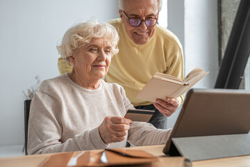 Woman making online purchase using credit card and looking with smiled face