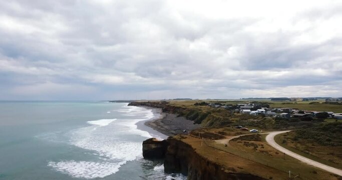 Flight over Waverley Beach's black sands and cliffs on a gloomy day - NZ