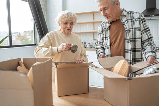 Happy retired senior couple moving into a new home and unpacking boxes