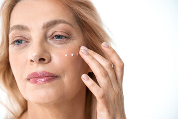 Woman applying wrinkle cream or anti-aging skin care cream