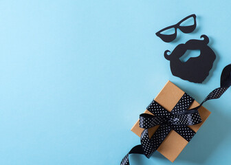 Fathers day concept with gift box and moustache and bread on blue background