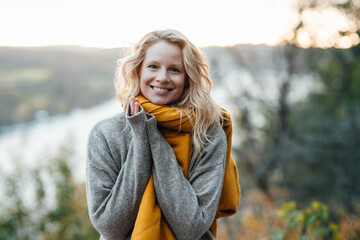 Blond woman in gray sweater smiling during sunset