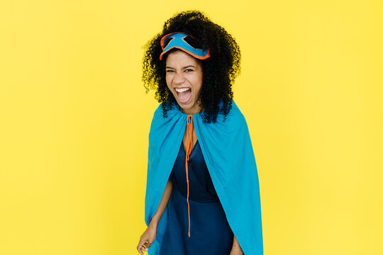 Woman wearing superhero costume shouting in front of yellow background