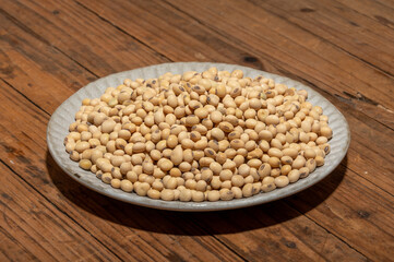 Soybeans placed in a bowl or plate are on the wood grain table