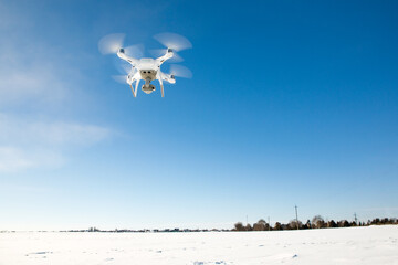 Drone flying above field covered with snow on sunny winter day