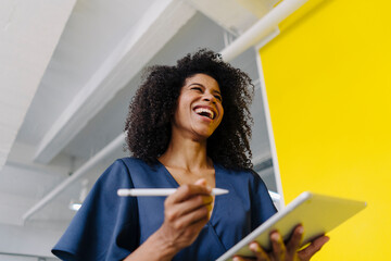 Mid adult female entrepreneur holding digital tablet and digitized pen in industry