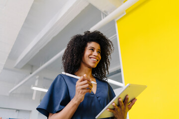 Smiling businesswoman holding digital tablet and digitized pen in industry