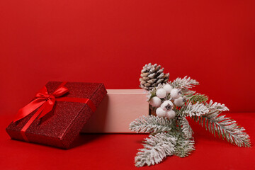 open red gift box with winter festive decoration on red background. Christmas podium for cosmetics...