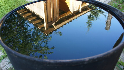 Reflection of a house in a barrel of water