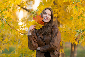 happy girl with school bag near autumn colorful leaves on rowanberry tree, nature