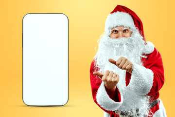 Smartphone mockup image, environment to showcase mobile app design, creative background. Smartphone for your advertising. Santa claus is standing next to a large smartphone. Christmas advertisement.