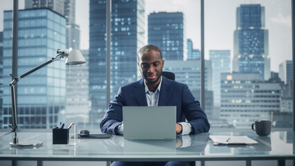 Portrait of Successful Black Businessman Working on Laptop Computer in His Big City Office....