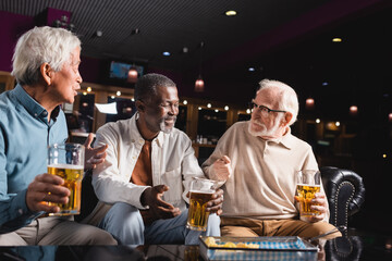 senior multicultural friends gesturing while talking in beer pub - Powered by Adobe