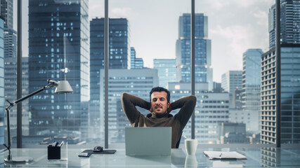 Portrait of Relaxed Brilliant Businessman Working on Laptop Computer in His Big City Office....