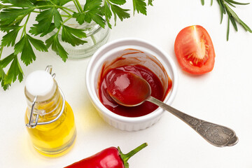 Spoon with tomato sauce in jar. Olive oil in glass bottle.
