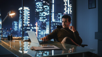Portrait of Thoughtful Successful Businessman Working on Laptop Computer in His Big City Office at...