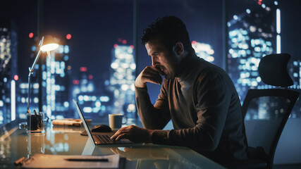 Portrait of Thoughtful Successful Businessman Working on Laptop Computer in His Big City Office at Night. Energetic Digital Entrepreneur does Data Analysis for e-Commerce Strategy.