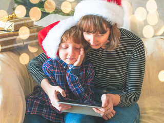 Mother and son in santa claus caps on couch, christmas