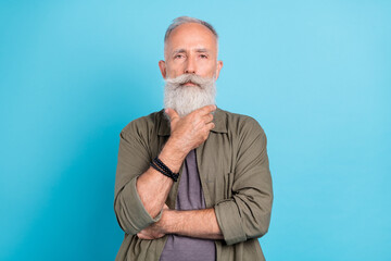 Photo of think old man touch beard wearing khaki shirt isolated over blue color background