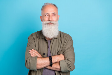 Photo of nice old man crossed arms look empty space wearing khaki shirt isolated over vivid blue color background