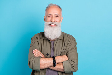 Photo of agent aged man crossed arms wearing khaki shirt isolated over vivid blue color background