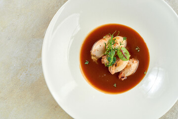 Stuffed squid in sauce in a white plate on a white tablecloth