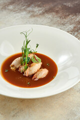 Stuffed squid in sauce in a white plate on a white tablecloth