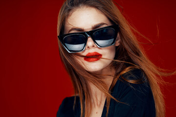 cheerful fashionable woman wearing sunglasses red lips posing red background