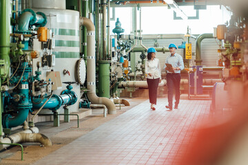 Male and female engineers discussing while walking in workshop